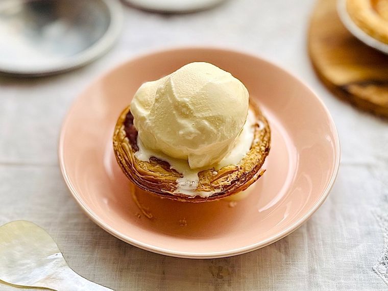 ピンク色の皿に置いたコストコのパステル・デ・ナタの上にバニラアイスクリームをトッピングしたところ