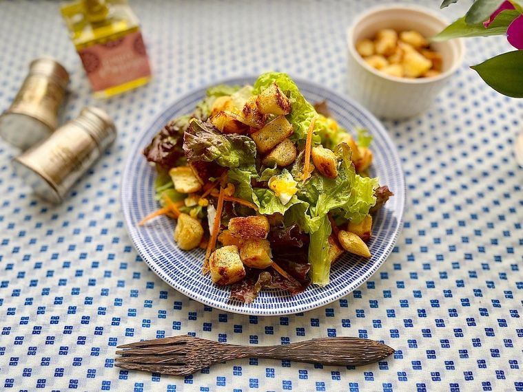 青いドット柄のテーブルクロスに置いた皿に盛り付けたコストコのコーンブレッドのクルトン入りサラダ、フォーク、スパイス