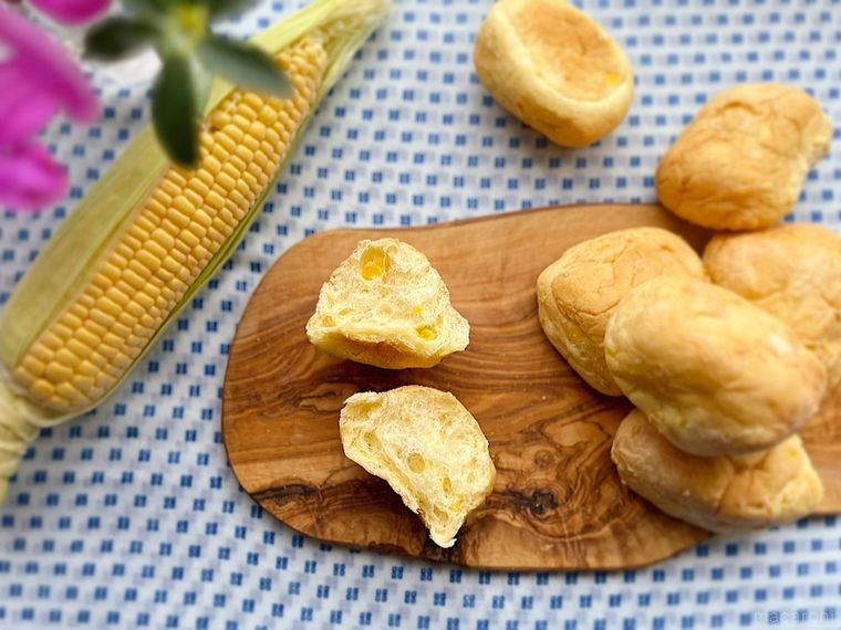ウッドボードの上で半分にカットして断面を見せたコストコのコーンブレッドロール、皮を半分むいたコーン