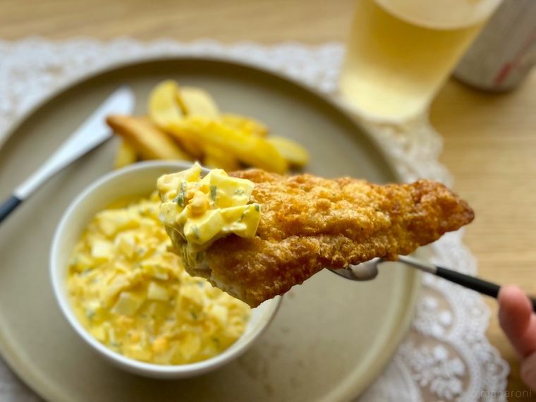 ひと切れフォークにとったコストコのフィッシュチップスにタルタルソースをつけているところ