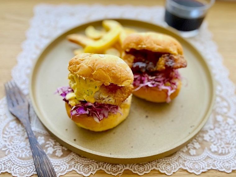 大きな皿に盛り付けたコストコのフィッシュチップス使ったフィッシュバーガー2個とフライドポテト、木製フォーク