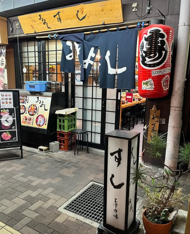 青いのれんがかかった寿司店まるよし外観
