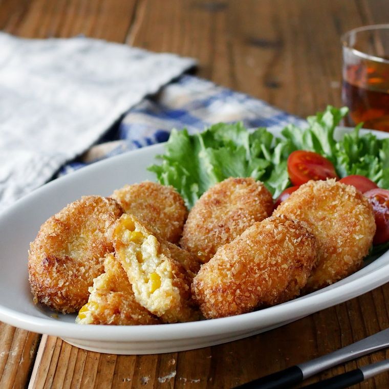 白い皿に盛り付けたコーンクリームコロッケと添えたミニトマト、レタス