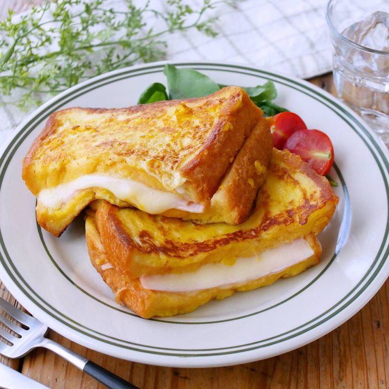 線が入った白い皿に盛り付けたコーンクリームフレンチトーストと添えたミニトマト