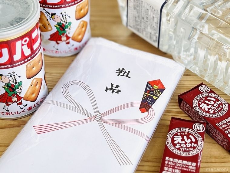 テーブルの上に粗品タオル、カンパン、非常用水、えいようかんが置かれている様子