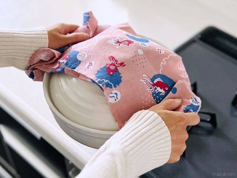 手ぬぐいを鍋つかみ代わりにして土鍋を持ち上げている様子