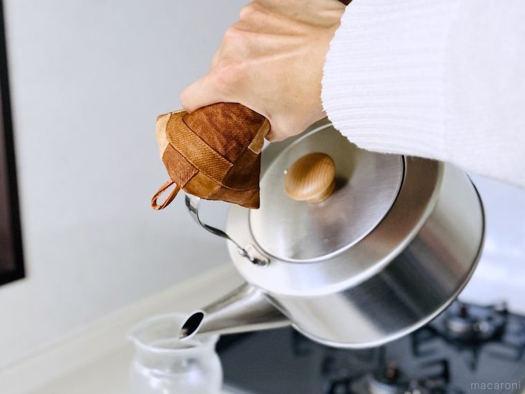 鍋敷きを鍋つかみ代わりにしてやかんを持っている様子