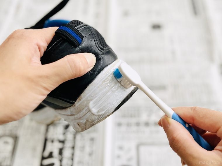 歯磨き粉をつけた歯ブラシでスニーカーのソールをこすっている様子
