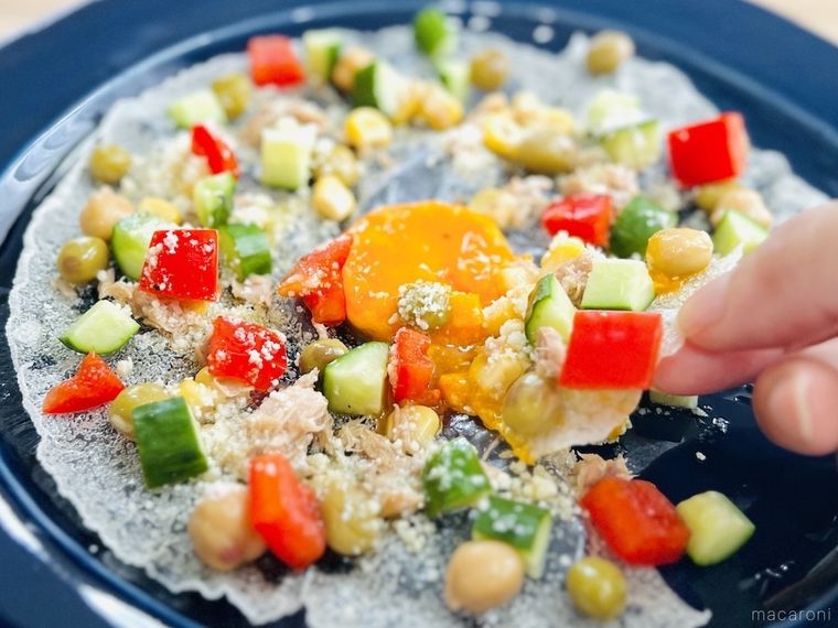 揚げたライスペーパーを手でちぎり、卵黄を絡めている様子