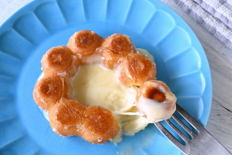 ちぎったポン・デ・リングにチーズソースを絡めてフォークで持ち上げる様子