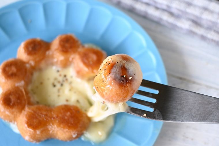 ブラックペッパーと白ワイン入りのチーズソースをポン・デ・リングに絡める様子