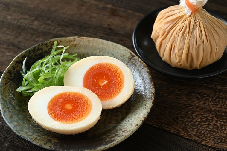 半分にカットしたみそ味玉を盛り付けた皿とラップに包まれたみそ味玉が並んでいる