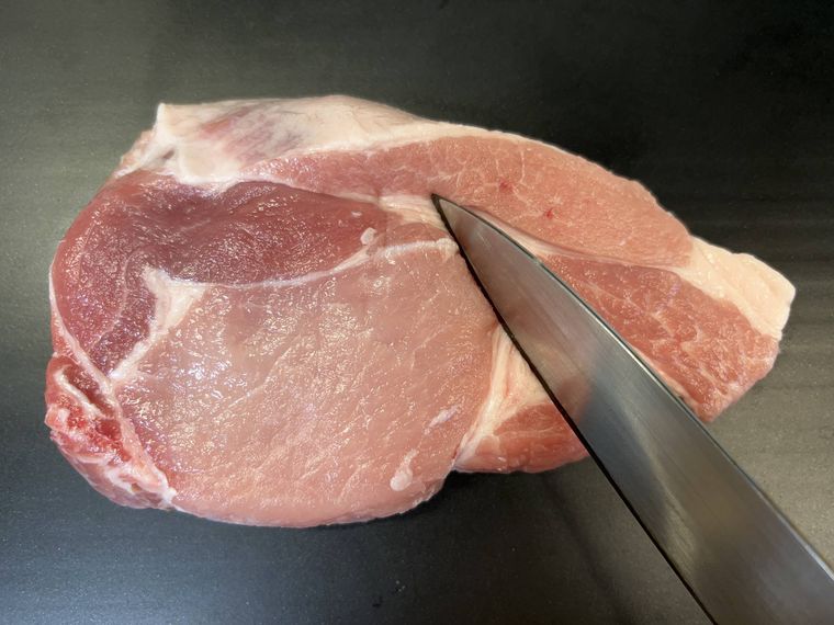 豚ロース肉に包丁を置く