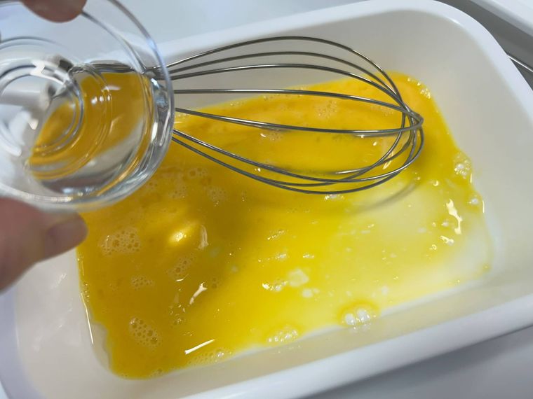 白いバットで溶いた卵、ガラスの小皿の油