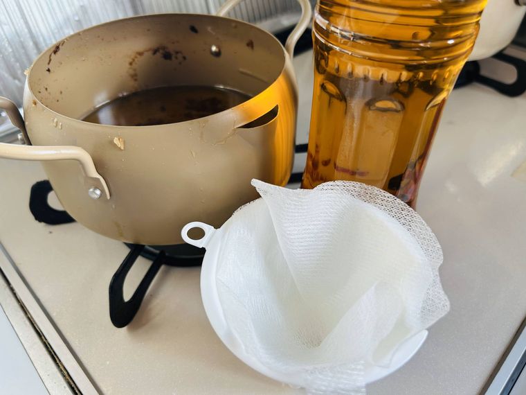 油が入ったベージュの鍋と白い漏斗、油が入ったペットボトル