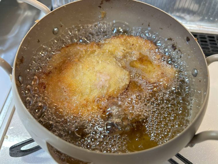 ベージュの鍋でとんかつを揚げる様子