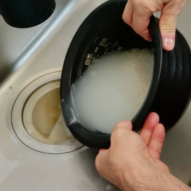 炊飯釜に入った研ぎ汁を流している様子