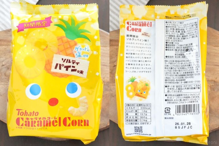 木のカッティングボードにのった黄色パッケージのキャラメルコーンとストライプの布とグリーン