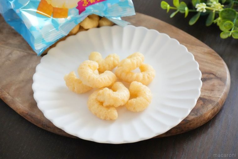 木のカッティングボードと白い皿にのったバニラ風味のキャラメルコーンと水色のパッケージ