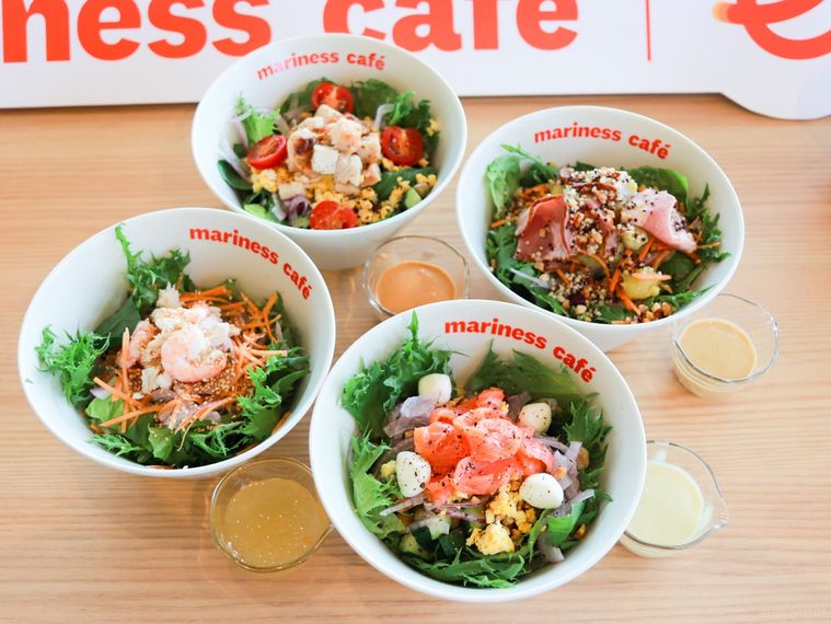 マリネスカフェのウェルネスサラダ4種が木製のカウンターテーブルに並んでいる