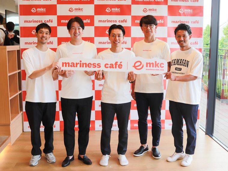 マリネスカフェに参加している各社の代表者がマリネスカフェのロゴプレートを持って横一列に並んでいる