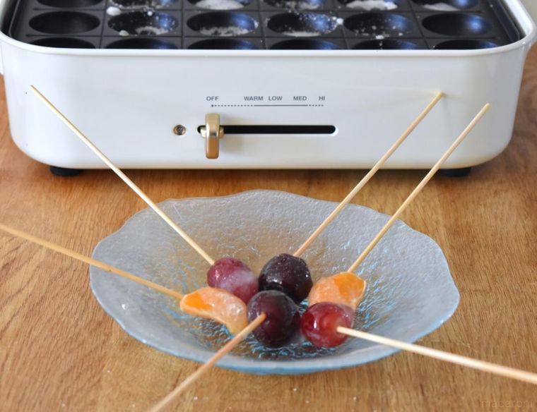 テーブルに置いたたこ焼きプレートと皿にのせたフルーツ飴