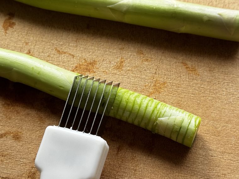 アスパラに100金のネギカッターをあてている様子