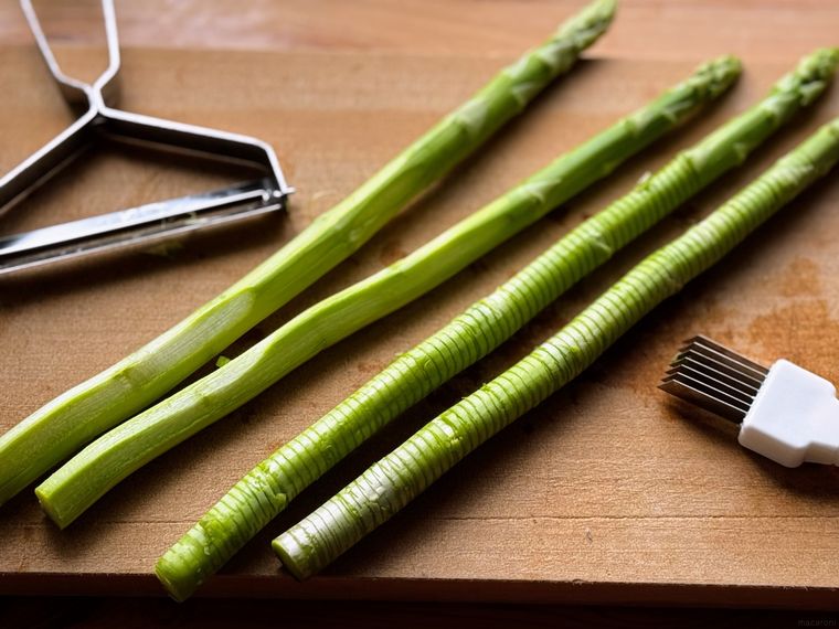 カッティングボードにのった下処理済みのアスパラ4本とピーラーとネギカッター