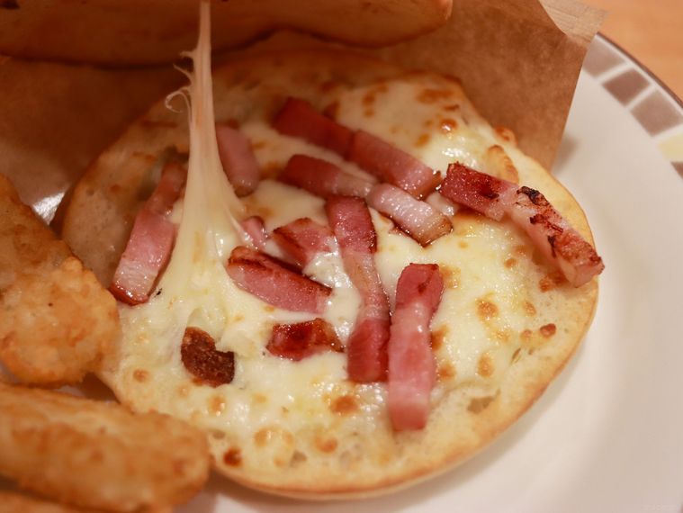 パンチェッタとチーズのパニーニを開いて中のチーズとベーコンを見せている様子