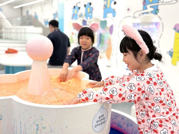 スライムに手を入れて遊ぶ子どもたち