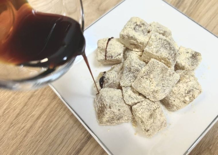 白い皿に盛り付けたわらび餅に、黒みつをかける様子