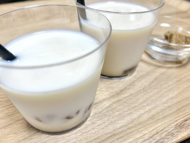 透明のコップに入ったわらび餅入り黒糖ミルクとガラスの小皿に入った黒糖