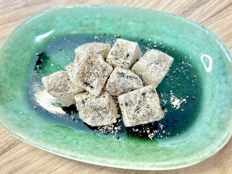 緑の皿に盛り付けた黒すりごまときな粉のわらび餅