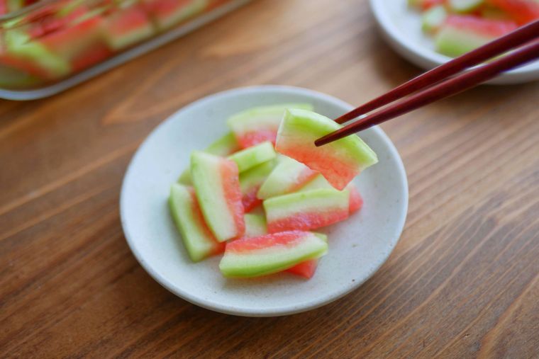 スイカの皮の漬物を箸で持ち上げる様子
