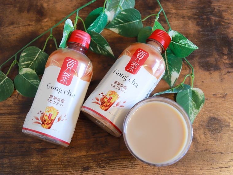 「貢茶 黒糖烏龍ミルクティー」2本とコップに入ったミルクティーを木製のテーブルの上に並べている