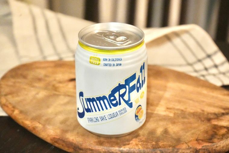 木のカッティングボードにのったスパークリング日本酒缶と生成色の布