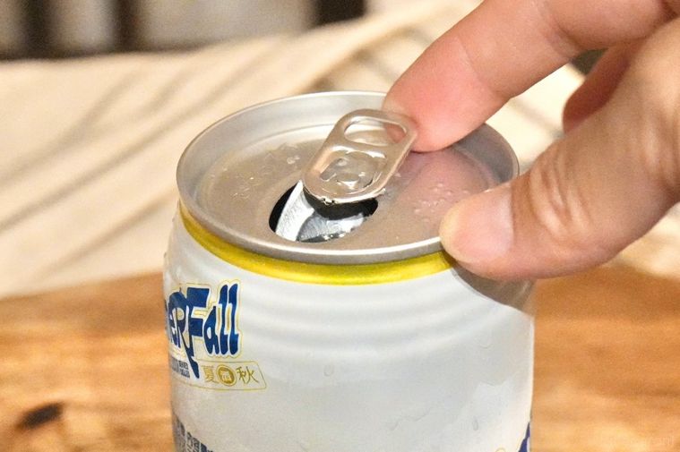 木のカッティングボードにのった日本酒スパークリングの白と黄色のパッケージと手