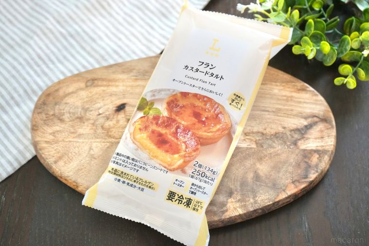 木のカッティングボードにのった冷凍のカスタードタルトとストライプの布とグリーン