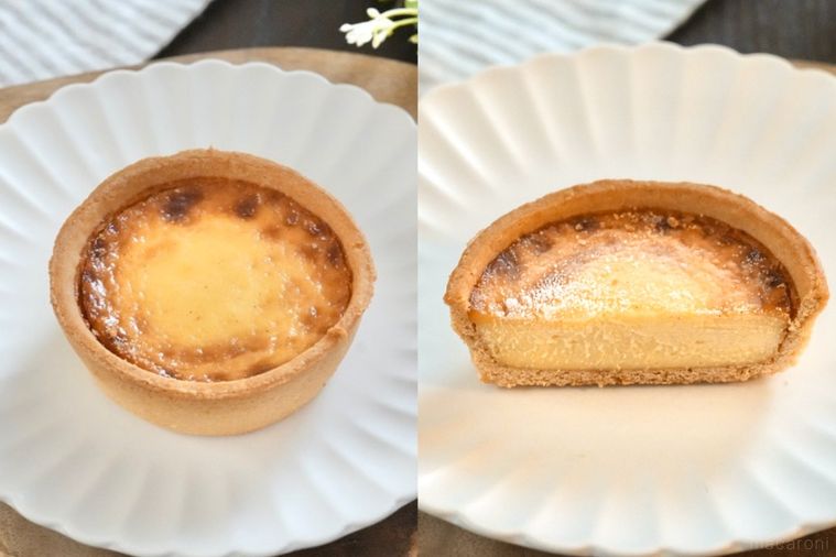木のカッティングボードと白い皿にのったカスタードタルトとストライプの布とグリーン
