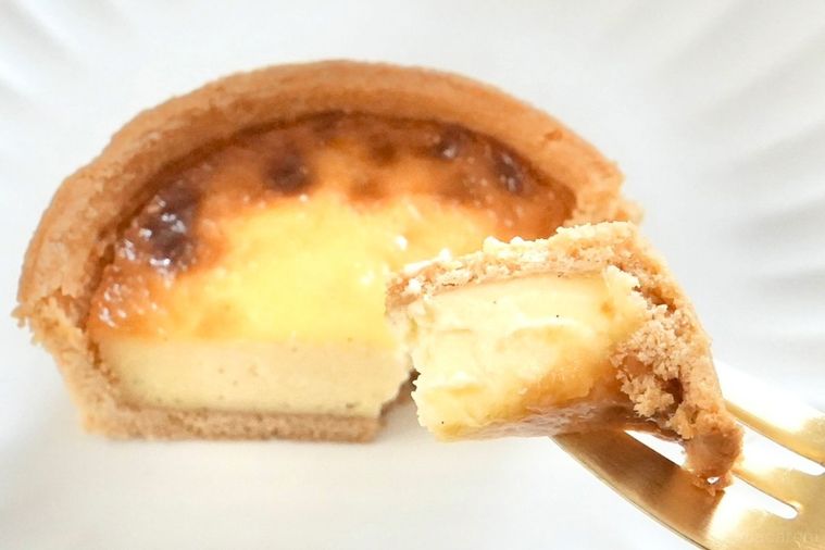 白い皿にのったカスタードタルトと金のフォークで食べる様子