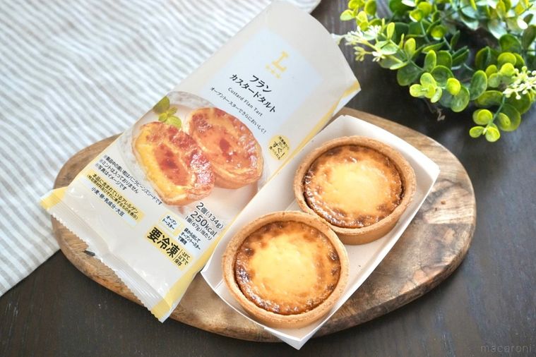木のカッティングボードにのったカスタードタルトのパッケージとストライプの布とグリーン
