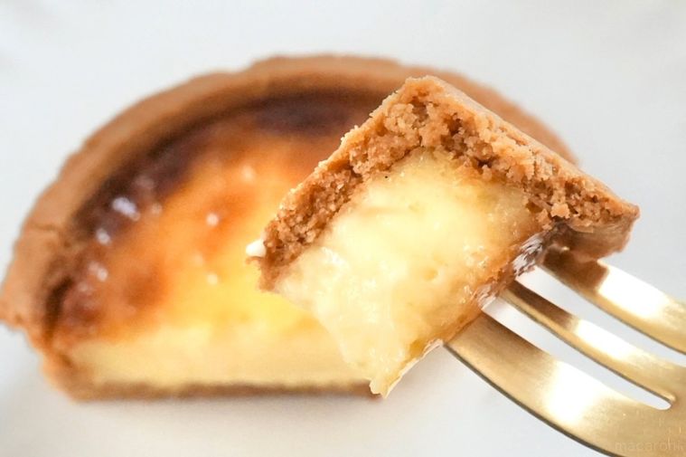 白い皿にのったカスタードタルトと金のフォークで食べる様子