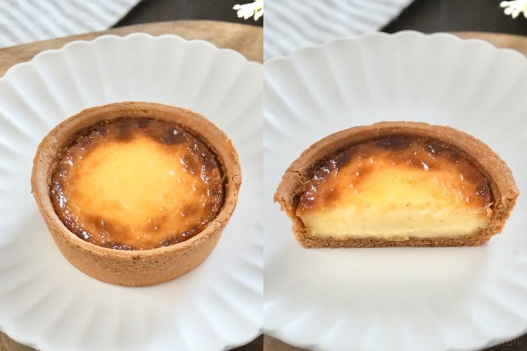 木のカッティングボードと白い皿にのったカスタードタルトとストライプの布とグリーン