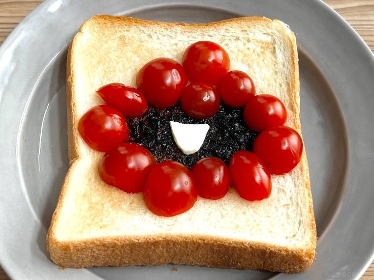 海苔の佃煮とミニトマトでデコレーションしたトーストにチーズをのせた様子