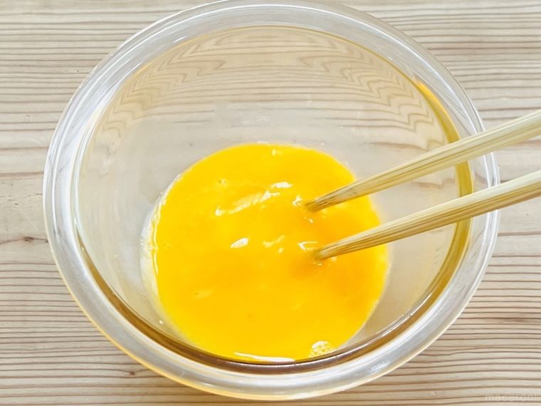 菜箸で卵を溶きほぐしている様子