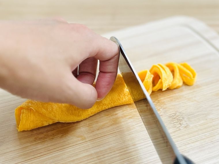 半解凍した薄焼き卵を細切りにしている様子