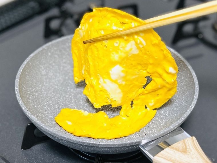 破れた薄焼き卵を箸で持ち上げている様子