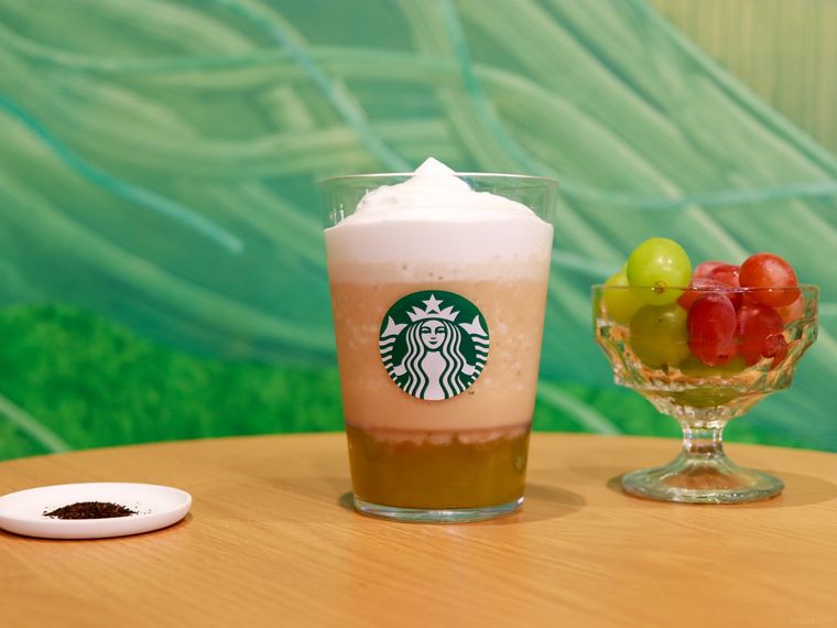 木製のテーブルの上にマスカット アールグレイ フローズン ティーと茶葉、グラスに入ったマスカットが置かれている