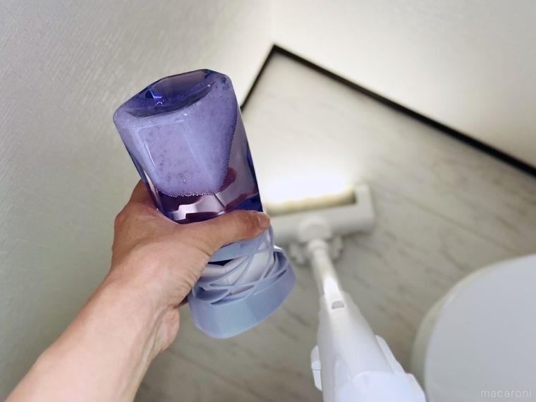 トイレの芳香剤を持ち上げて掃除機をかけている様子