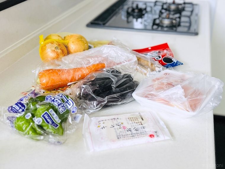 キッチンの調理台にピーマン、にんじん、なす、玉ねぎ、肉などが置かれている様子